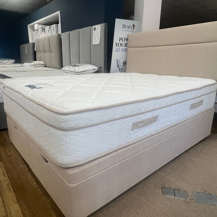 White mattress on a wooden platform with a box in the background