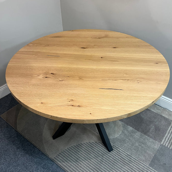 Round wooden table in a room with a gray carpet