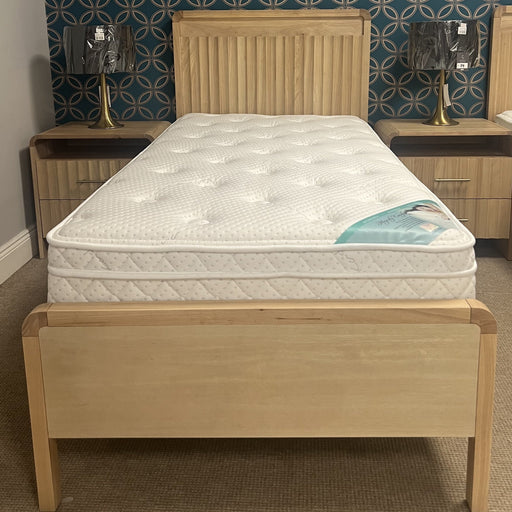 Wooden bed with a mattress in a bedroom setting